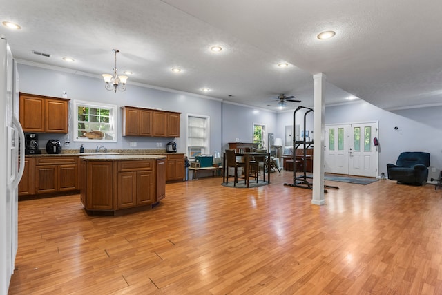 kitchen featuring pendant lighting, ceiling fan with notable chandelier, light hardwood / wood-style floors, and sink