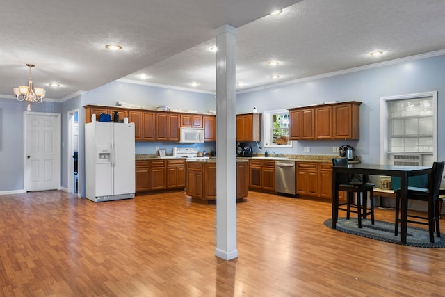 kitchen featuring ornamental molding, decorative columns, light wood-type flooring, an inviting chandelier, and white appliances