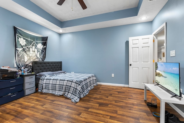 bedroom featuring a tray ceiling, dark hardwood / wood-style floors, and ceiling fan