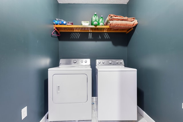 clothes washing area with washing machine and dryer and light tile floors