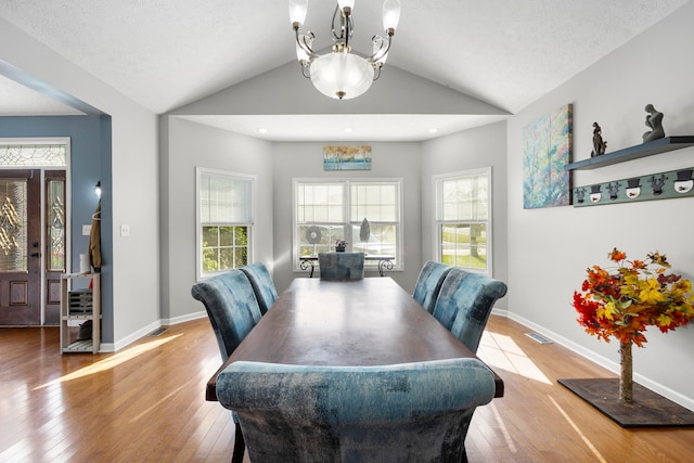 dining room featuring a notable chandelier, lofted ceiling, and wood-type flooring