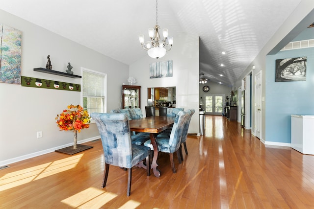 dining area with high vaulted ceiling, an inviting chandelier, and wood-type flooring