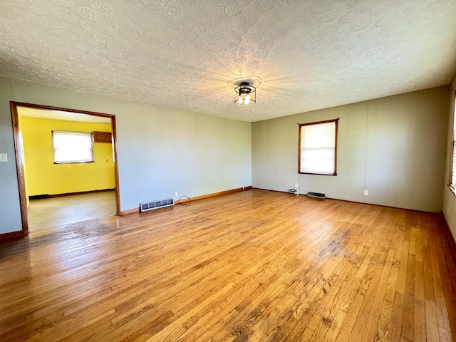 unfurnished room with plenty of natural light, hardwood / wood-style flooring, and a textured ceiling