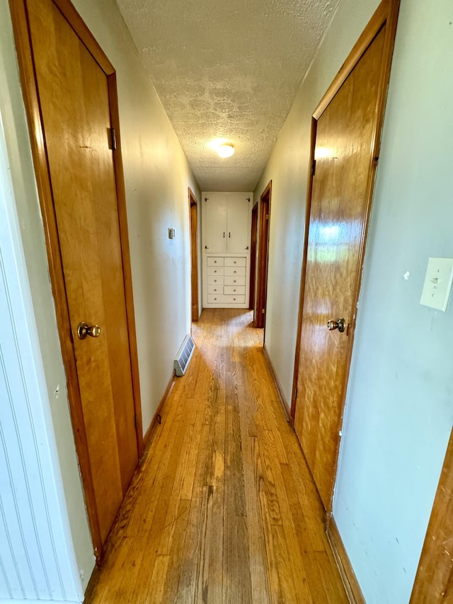 hall featuring light hardwood / wood-style floors and a textured ceiling