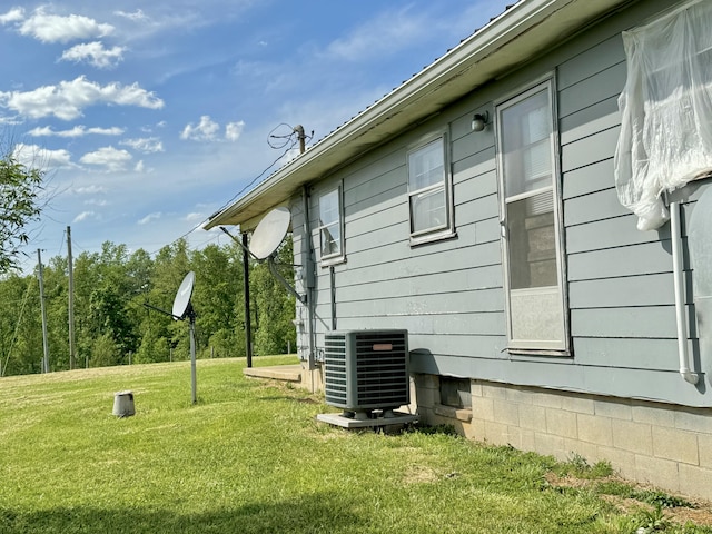 view of side of home featuring a yard and central AC