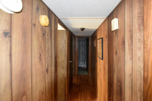 hallway with a textured ceiling, wood walls, and wood-type flooring