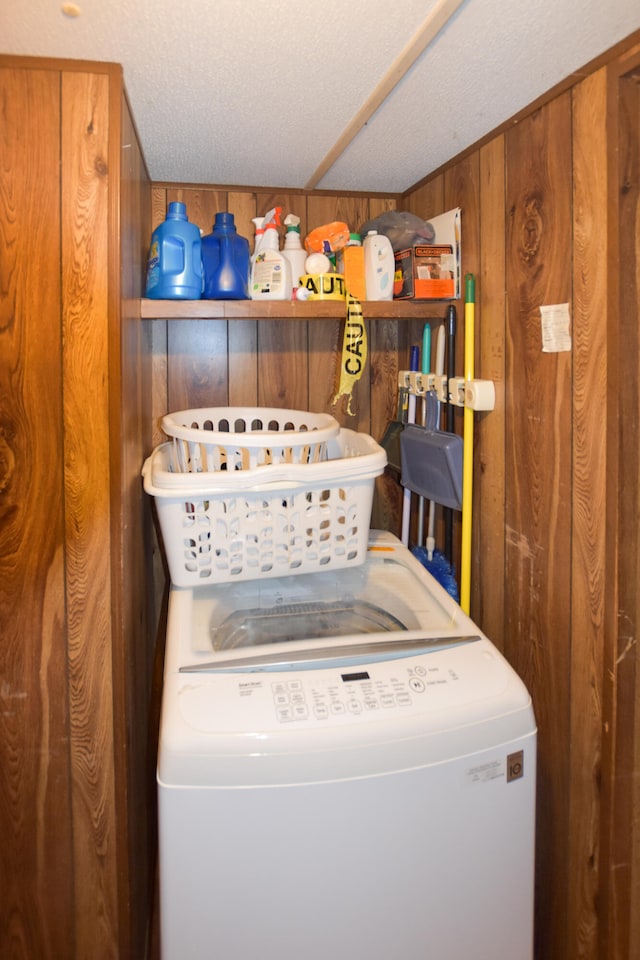 laundry room with a textured ceiling and wooden walls