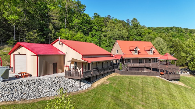 rear view of house with a wooden deck, an outdoor structure, a garage, and a yard