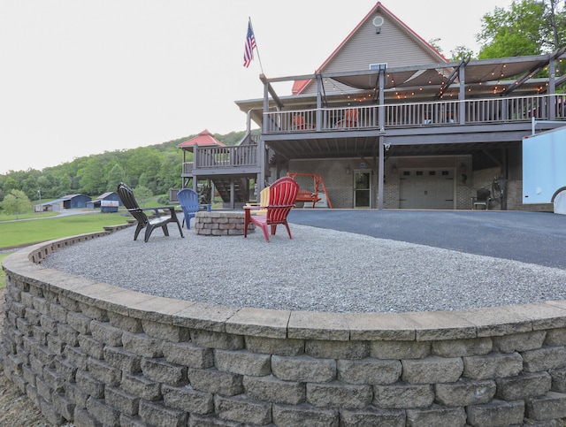 back of property with a wooden deck, a patio, and an outdoor fire pit