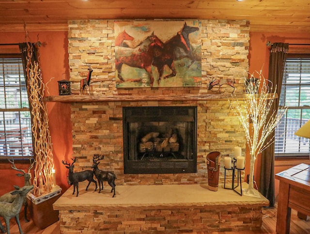 sitting room with a stone fireplace, hardwood / wood-style floors, and wooden ceiling