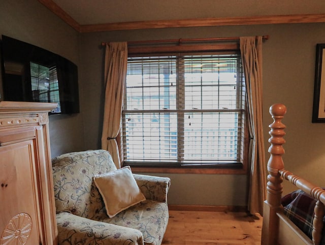 sitting room featuring light wood-type flooring, crown molding, and a wealth of natural light