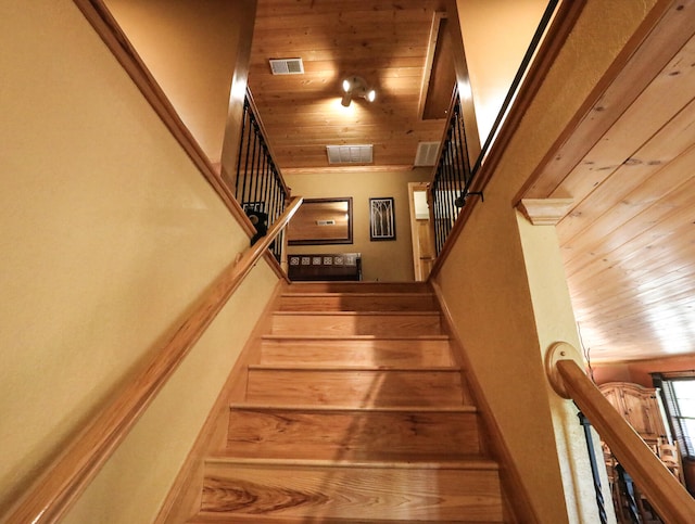 stairway featuring a towering ceiling and wooden ceiling