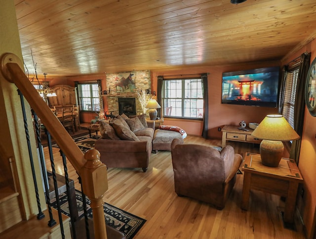 living room featuring light wood-type flooring, wood ceiling, a fireplace, and a notable chandelier