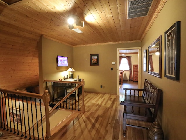 hallway featuring wood-type flooring, wooden ceiling, and crown molding