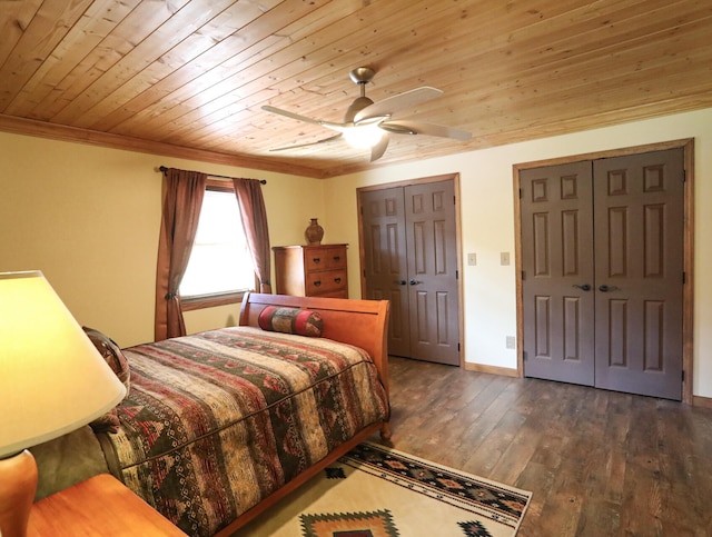 bedroom featuring dark wood-type flooring, multiple closets, ornamental molding, ceiling fan, and wooden ceiling