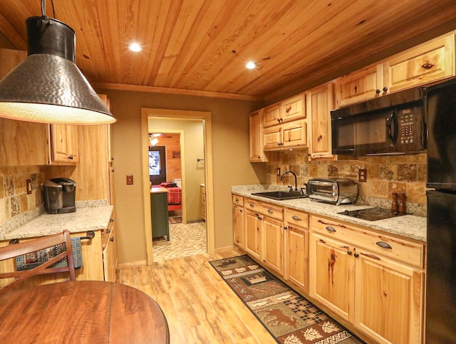 kitchen with light stone counters, hanging light fixtures, sink, black appliances, and light wood-type flooring