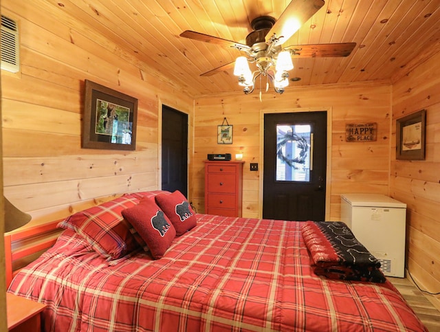 bedroom with wood ceiling, wood walls, fridge, ceiling fan, and hardwood / wood-style floors