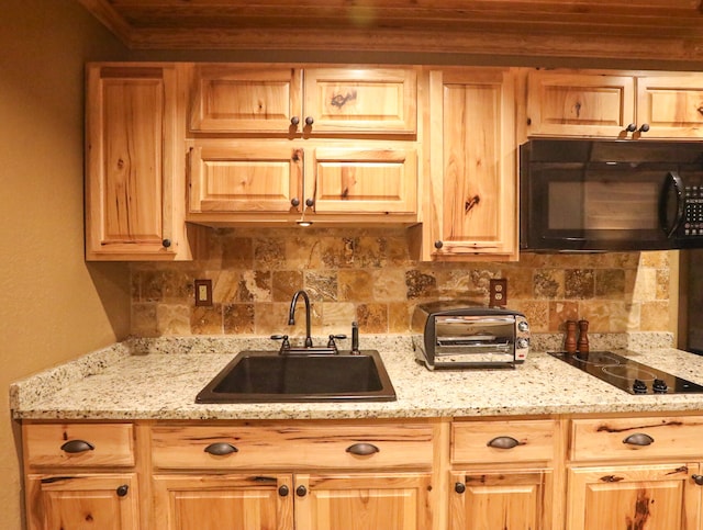 kitchen featuring light stone countertops, backsplash, sink, and black appliances