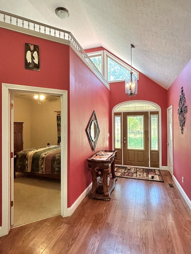 entrance foyer featuring a notable chandelier, high vaulted ceiling, a textured ceiling, and hardwood / wood-style flooring