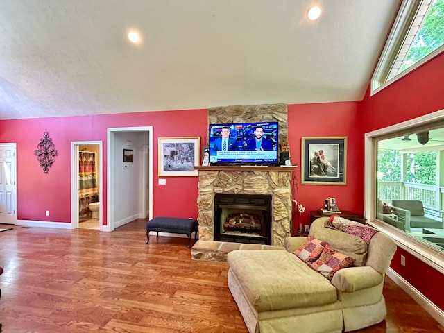 living room featuring a textured ceiling, vaulted ceiling, a fireplace, and wood-type flooring