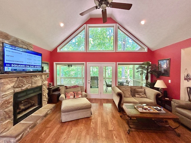 living room featuring a fireplace, ceiling fan, hardwood / wood-style floors, high vaulted ceiling, and a textured ceiling