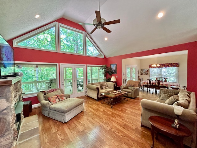 living room with a healthy amount of sunlight, hardwood / wood-style floors, high vaulted ceiling, and ceiling fan with notable chandelier