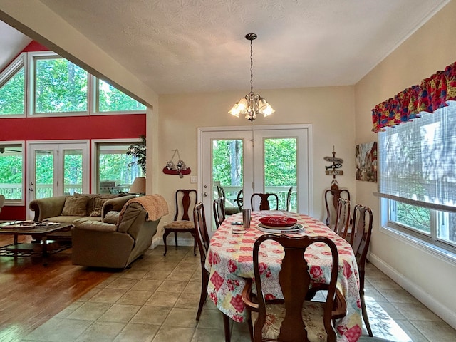 dining area with an inviting chandelier, a textured ceiling, hardwood / wood-style flooring, and french doors