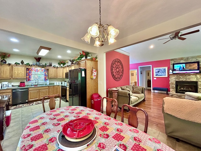 tiled dining room with sink, a fireplace, and ceiling fan with notable chandelier