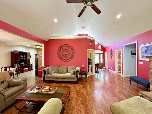 living room with vaulted ceiling, hardwood / wood-style floors, ceiling fan, and a textured ceiling