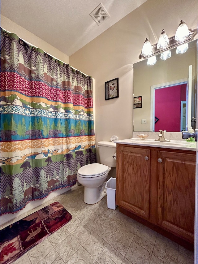 bathroom with a textured ceiling, vanity, toilet, and tile floors