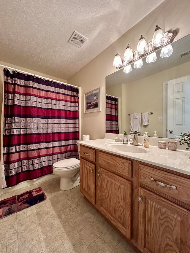 bathroom with tile flooring, a textured ceiling, toilet, and vanity