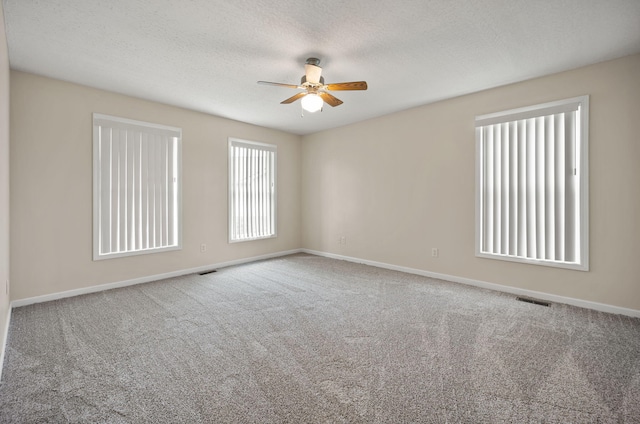 empty room featuring ceiling fan, a textured ceiling, and carpet