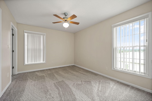 unfurnished room with ceiling fan and carpet