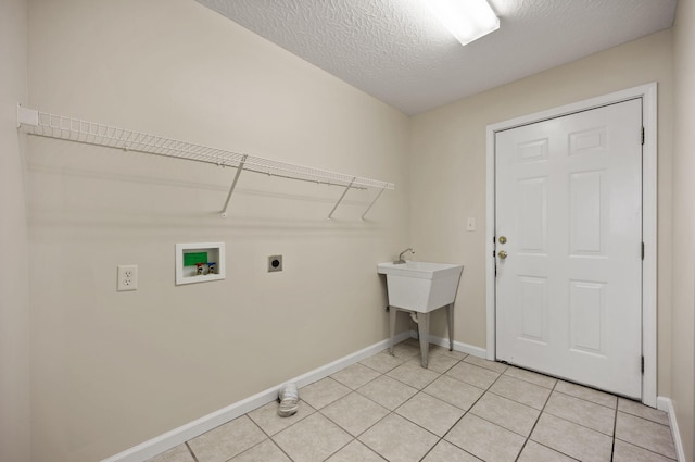 clothes washing area with a textured ceiling, hookup for an electric dryer, washer hookup, and light tile patterned floors