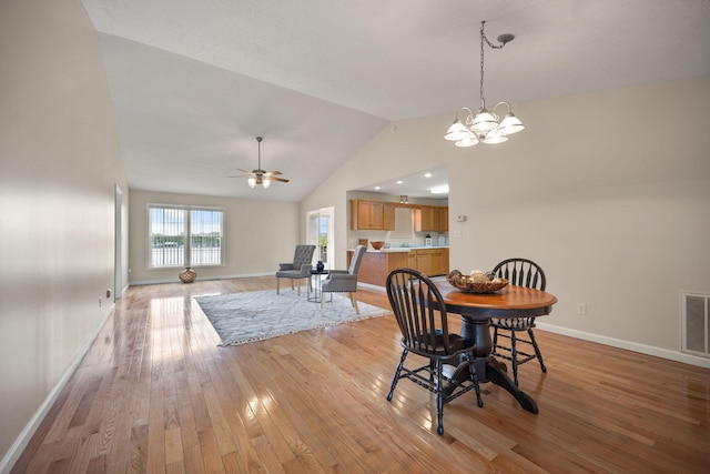 dining room with high vaulted ceiling, light wood-type flooring, and ceiling fan with notable chandelier