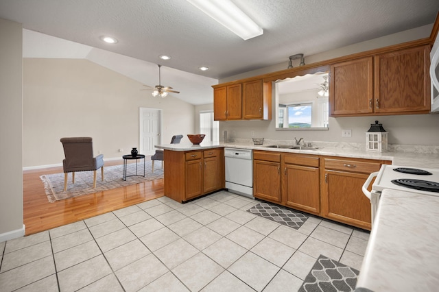 kitchen featuring light hardwood / wood-style flooring, ceiling fan, kitchen peninsula, dishwasher, and vaulted ceiling