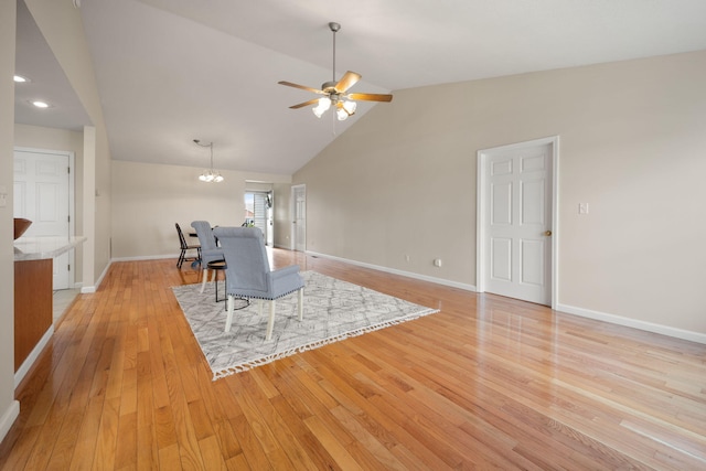 living room featuring high vaulted ceiling, light wood-type flooring, and ceiling fan with notable chandelier