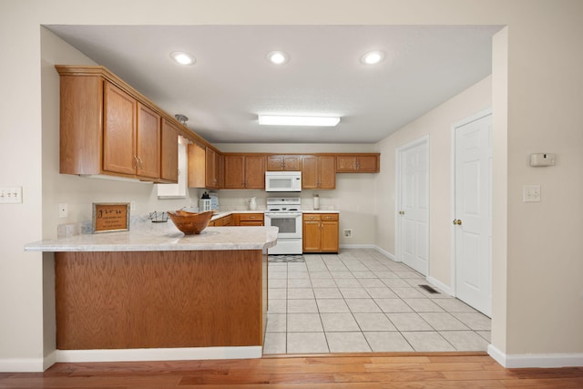 kitchen with white appliances, light wood-type flooring, light stone counters, and kitchen peninsula