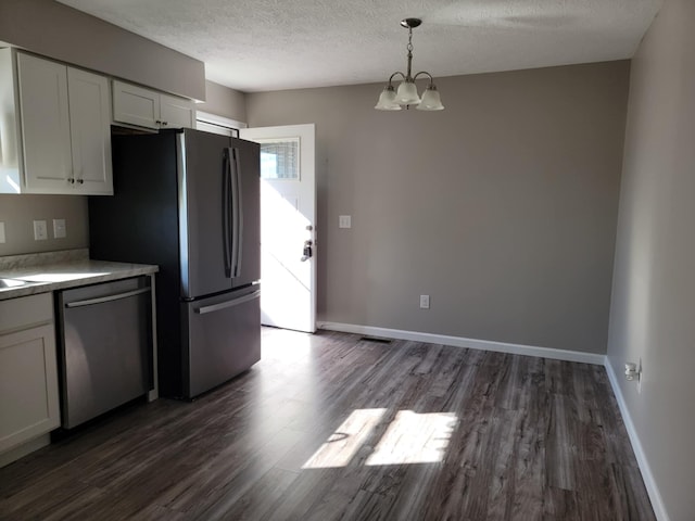 kitchen with appliances with stainless steel finishes, dark hardwood / wood-style floors, white cabinetry, and decorative light fixtures