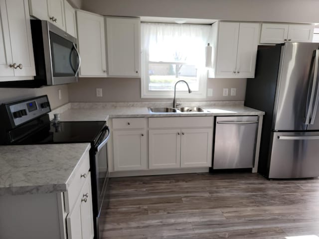 kitchen featuring white cabinetry, sink, stainless steel appliances, and wood-type flooring