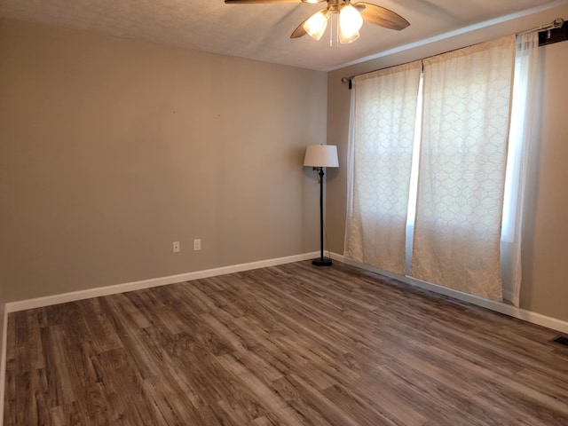 empty room featuring a textured ceiling, ceiling fan, and dark wood-type flooring