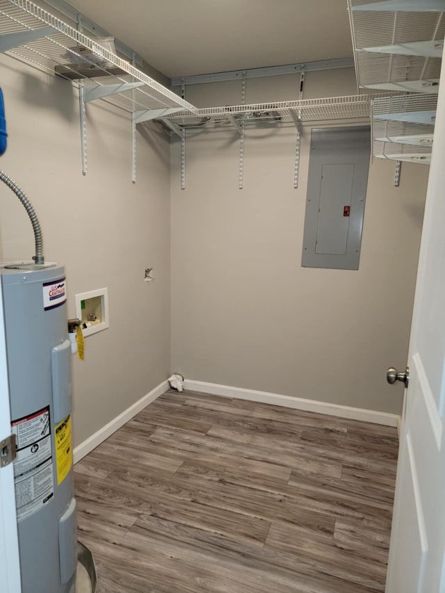 laundry area with electric panel, water heater, hookup for a washing machine, and hardwood / wood-style flooring