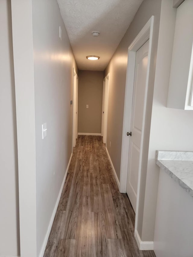 hallway with a textured ceiling and hardwood / wood-style flooring