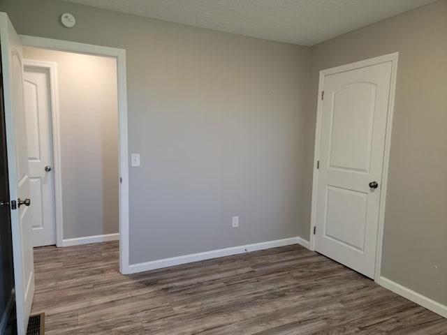 unfurnished bedroom featuring a textured ceiling and hardwood / wood-style flooring