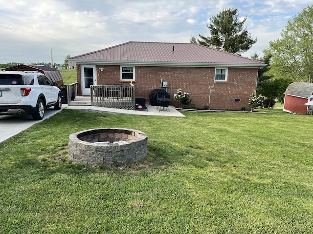 rear view of property featuring a lawn, a patio, and an outdoor fire pit