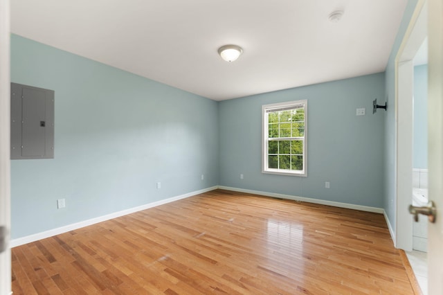 empty room with electric panel and light wood-type flooring