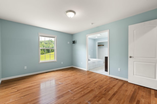 unfurnished bedroom featuring connected bathroom and light hardwood / wood-style floors