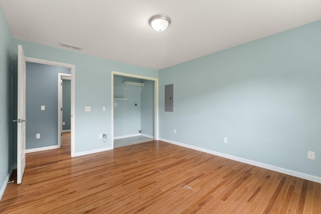 unfurnished bedroom with wood-type flooring, electric panel, and a closet