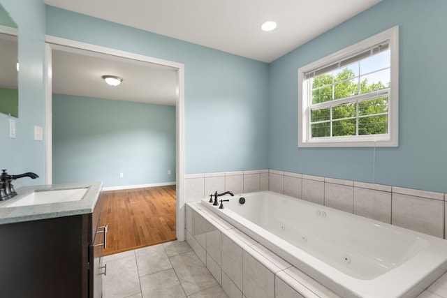 bathroom featuring vanity, tile patterned flooring, and a relaxing tiled tub