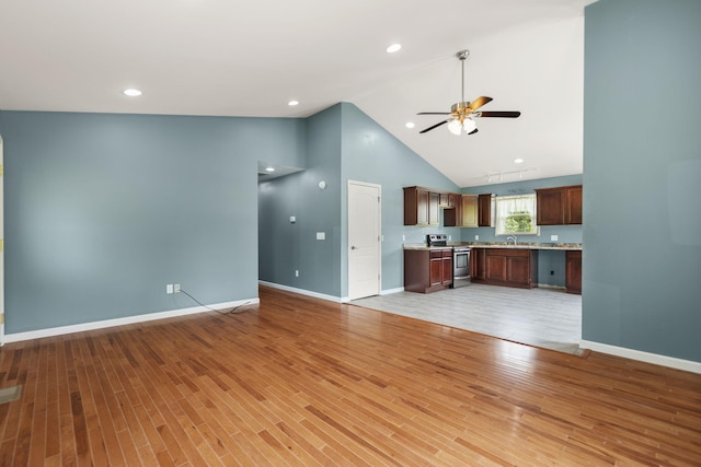 unfurnished living room featuring ceiling fan, high vaulted ceiling, sink, and light hardwood / wood-style flooring